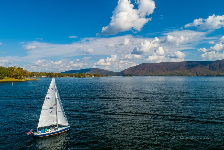 A sailboat glides across the lake toward Smith Mountain