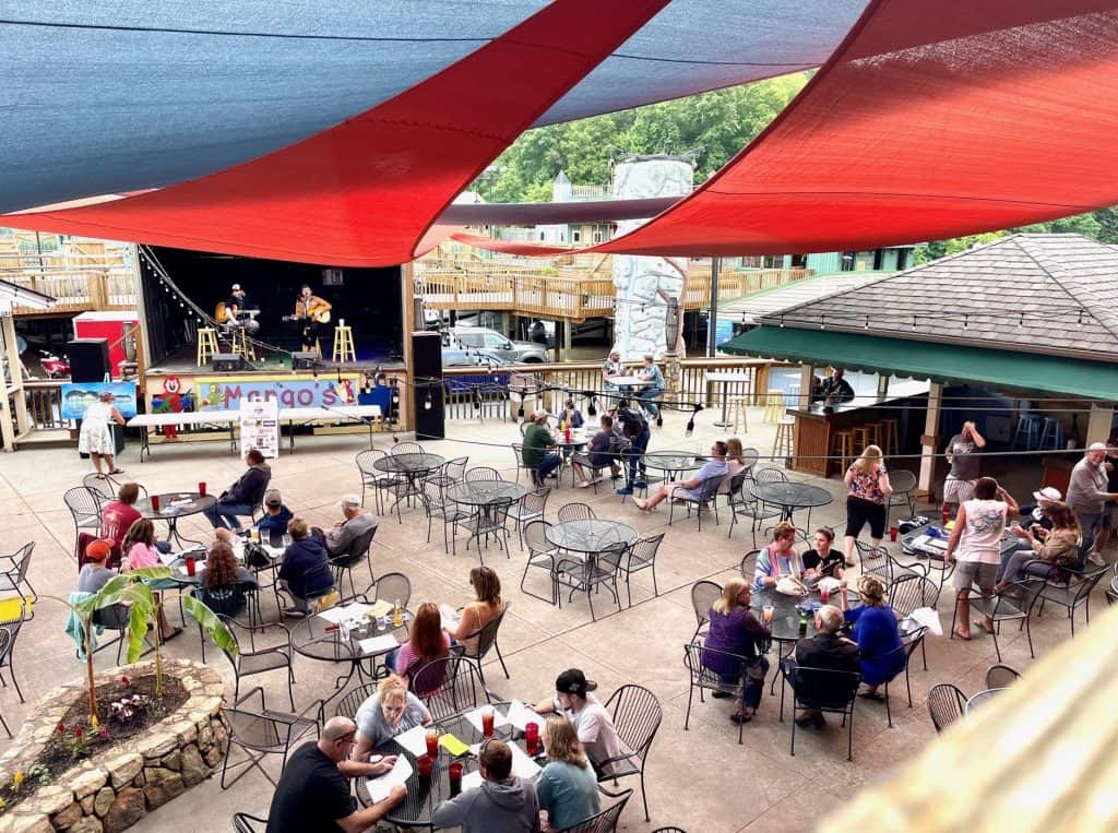 Patrons eat and drink on the lakeside patio while a duo plays live music on the stage