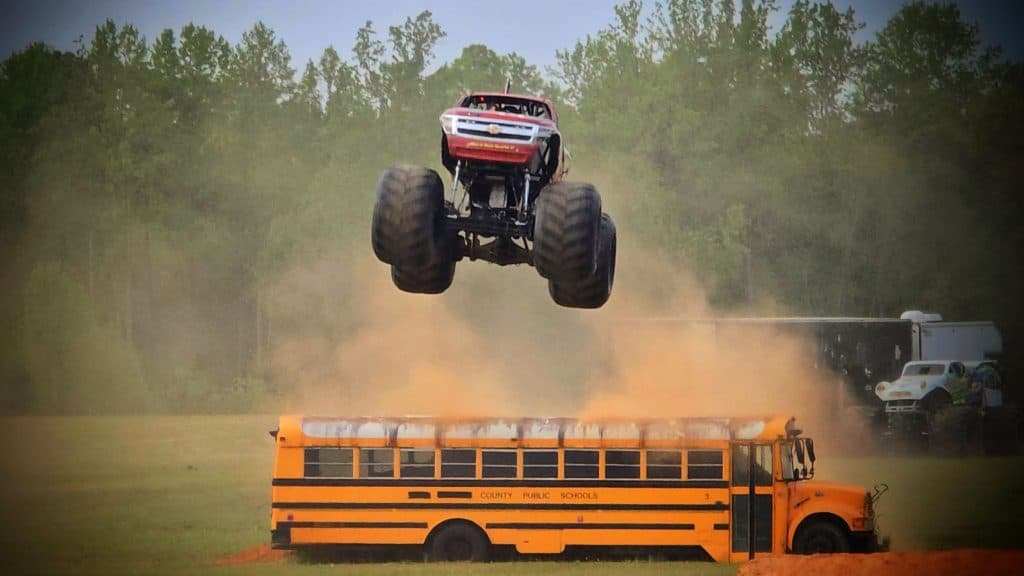 Monster truck jumping yellow school bus.