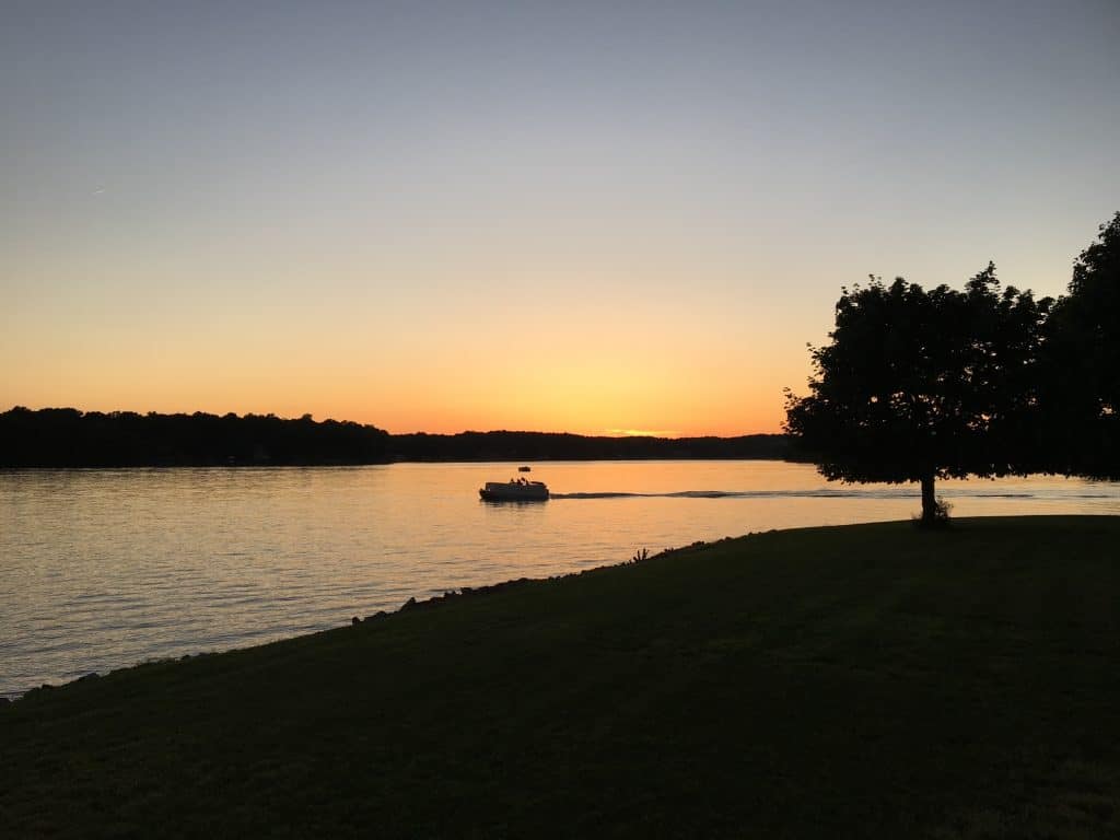  Pontoon gliding across smooth water of Smith Mountain Lake at sunset