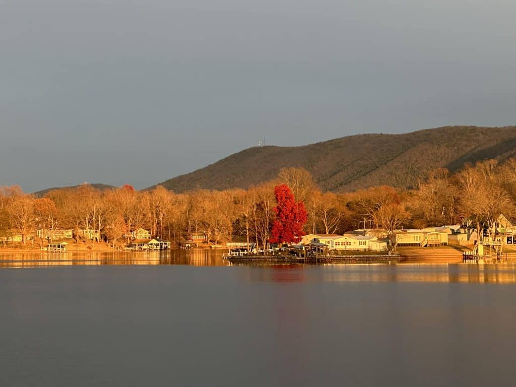 Vibrant red and orange trees set behind the calm waters of Smith Mountain Lake.