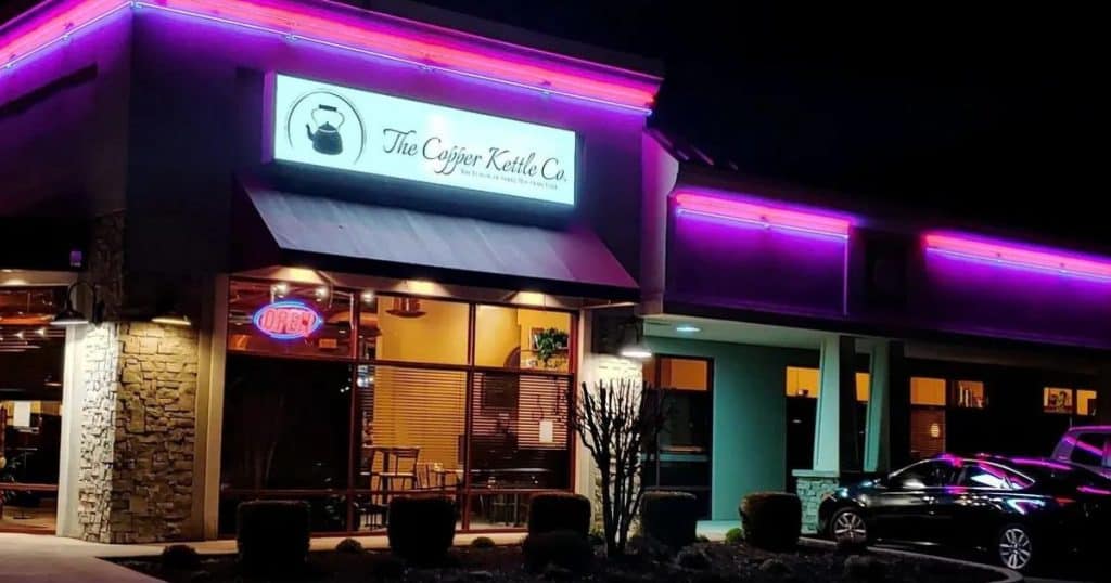 Purple lights enhance the exterior signage welcoming patrons to The Copper Kettle at night.