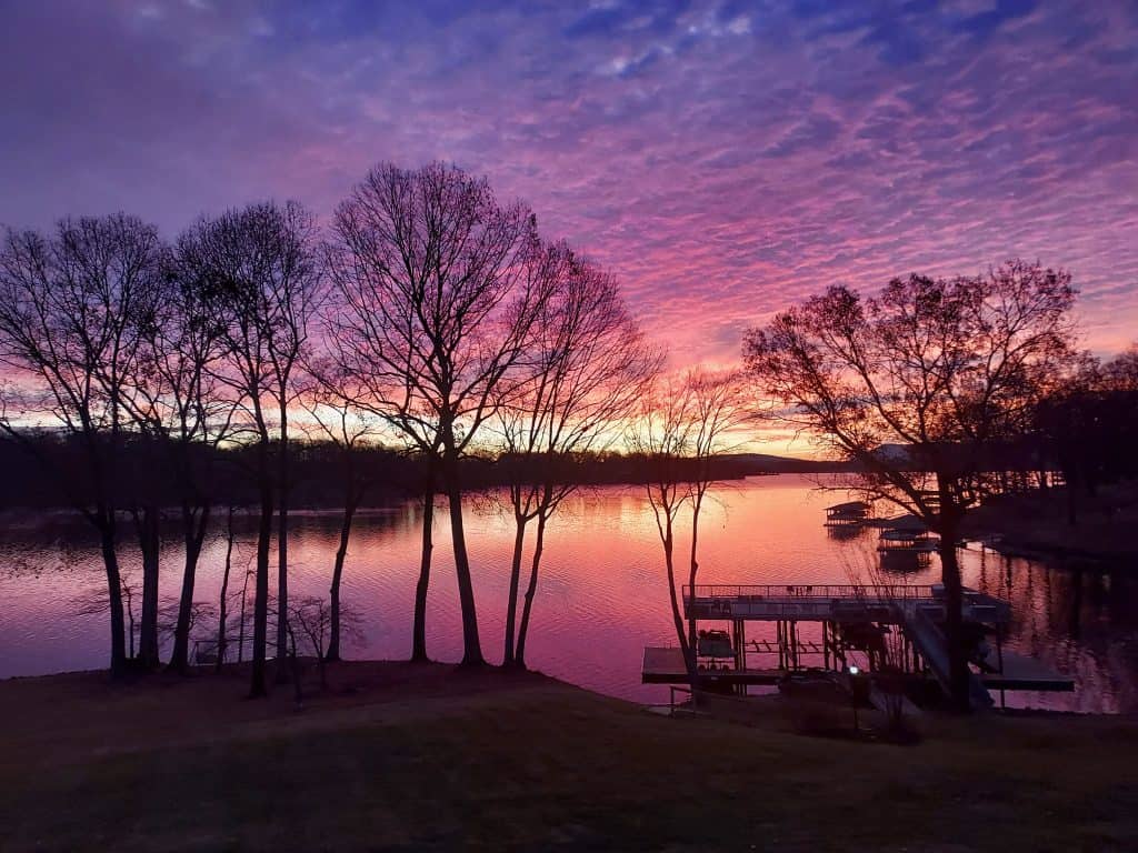 A purple sky reflects on a calm Smith Mountain Lake at sunrise in The Waterfront.