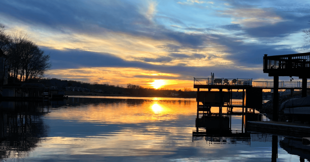 Yellow sun setting over Smith Mountain Lake, Virginia, with boat docks on the right.