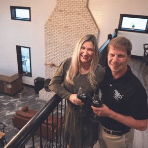 the owners of wind vineyards stand in their rustic barn tasting room