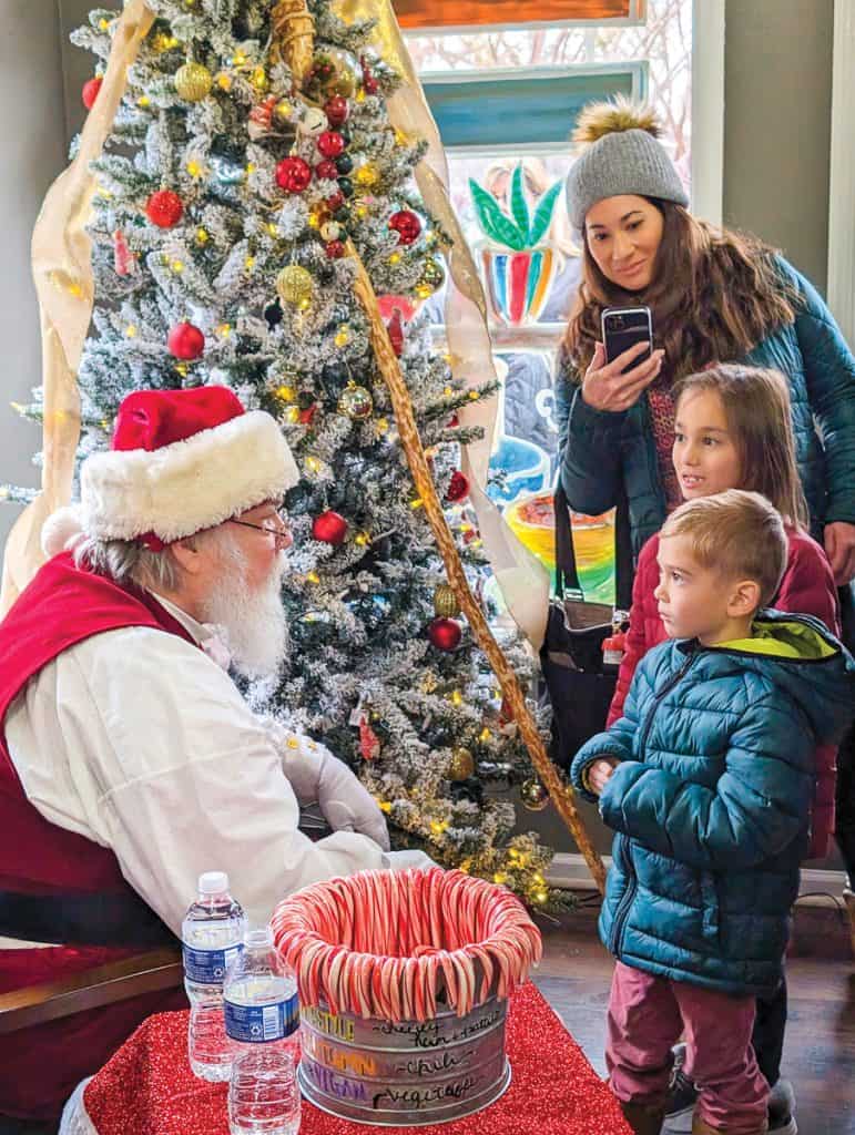 Santa speaks to children at SML Coffee House while their mom takes photos.