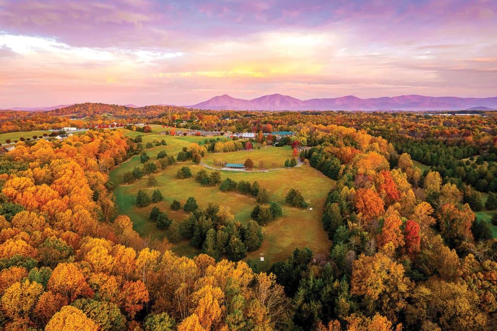 An aerial view of colorful fall foliage at Falling Creek in Bedford County with Peaks of Otter in the background.