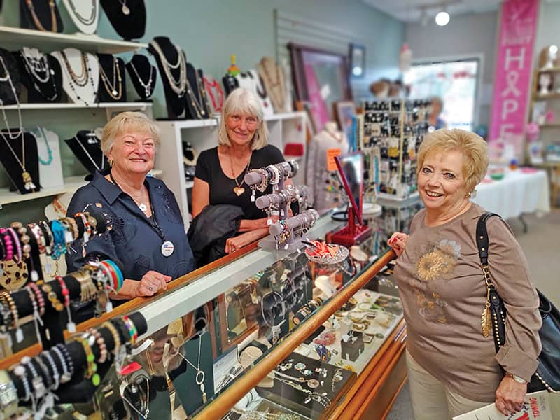 From left, Pende Ford and Dee Kropf help Bonnie Berkery select a piece of jewelry at The Discovery Shop’s 20th anniversary celebration in September 2024