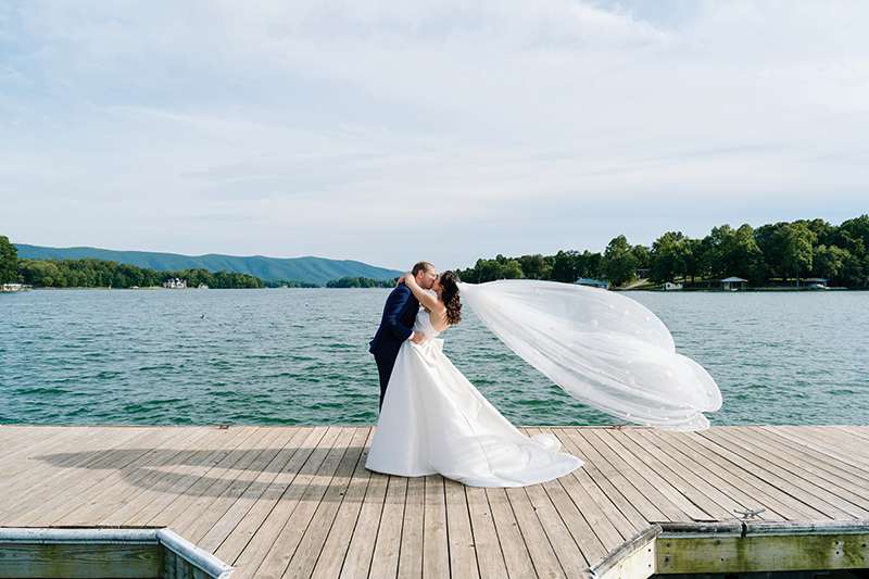 Bride and groom kissing on dock with Smith Mountain Lake in the background