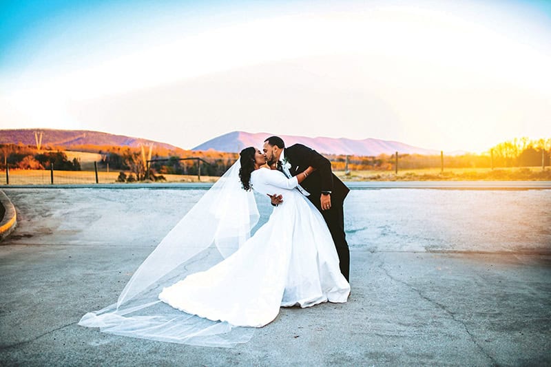 A bride and groom kiss with Smith Mountain in the background.