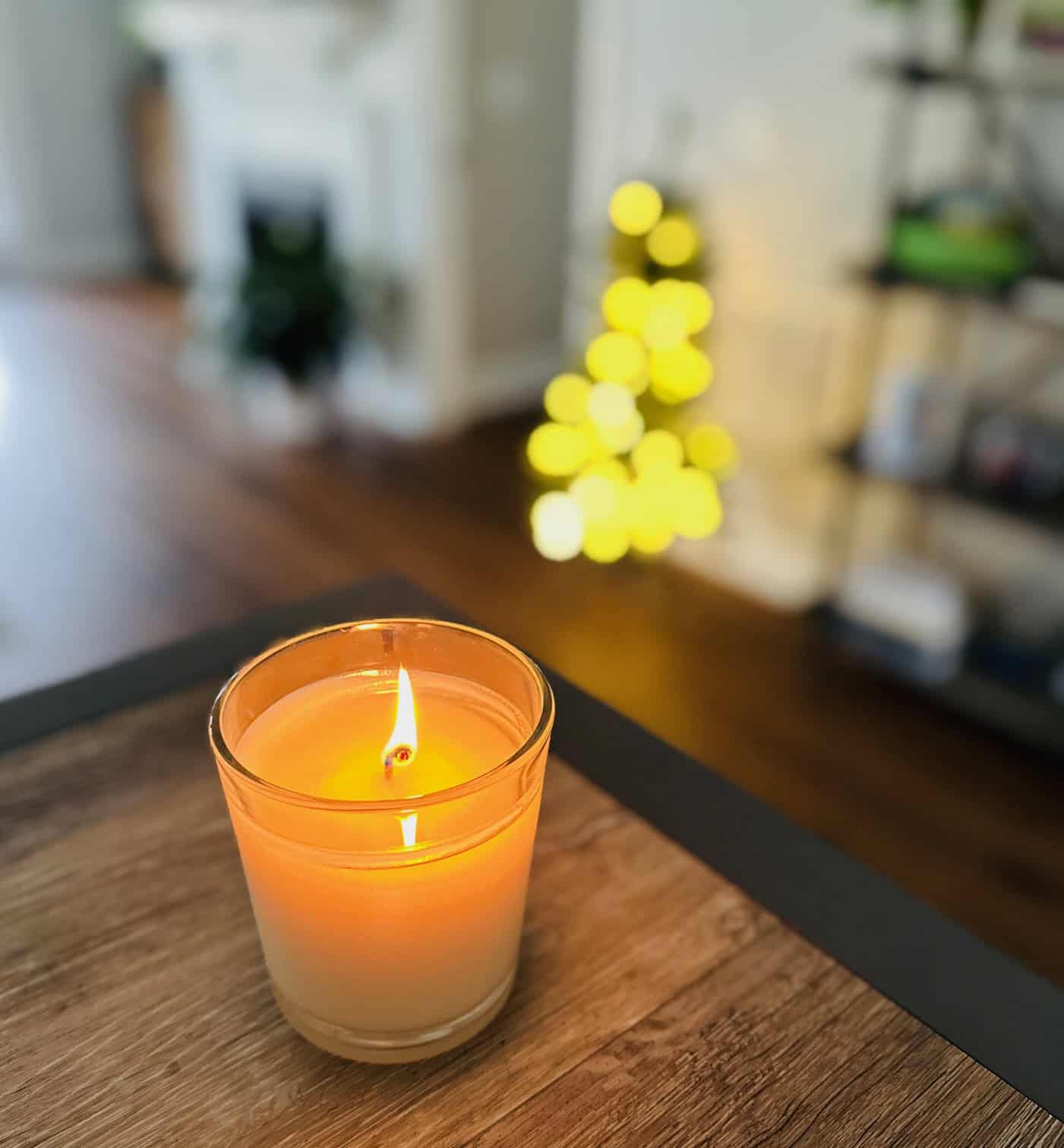 Candle burning with small Christmas tree in background