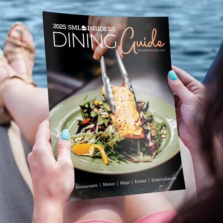 Photo of a woman holding the Smith Mountain Lake Dining Guide while sitting lakeside.