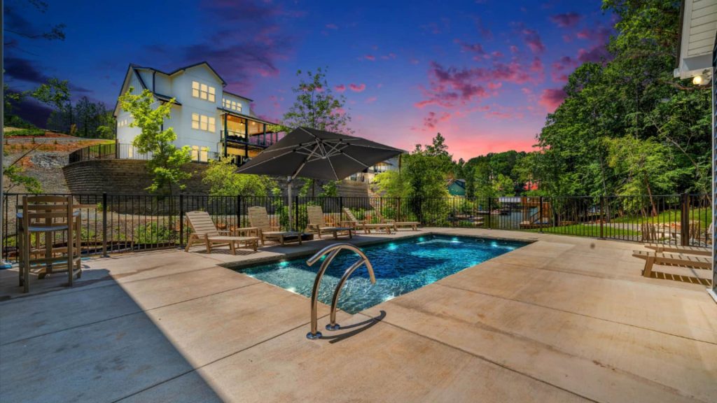 Purple sunset behind soaring three-story house with shimmering pool