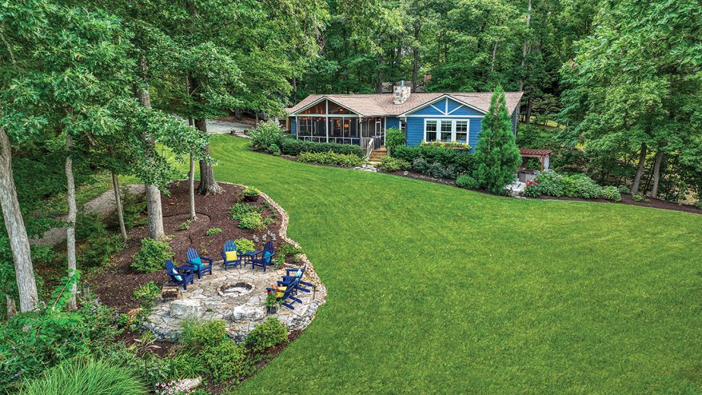 Rear exterior with covered patio and stone fireplace overlooking Smith Mountain Lake on the charity home tour.