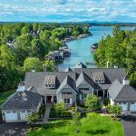 Shoreline exterior view of home framed by mature trees and water on the charity home tour.