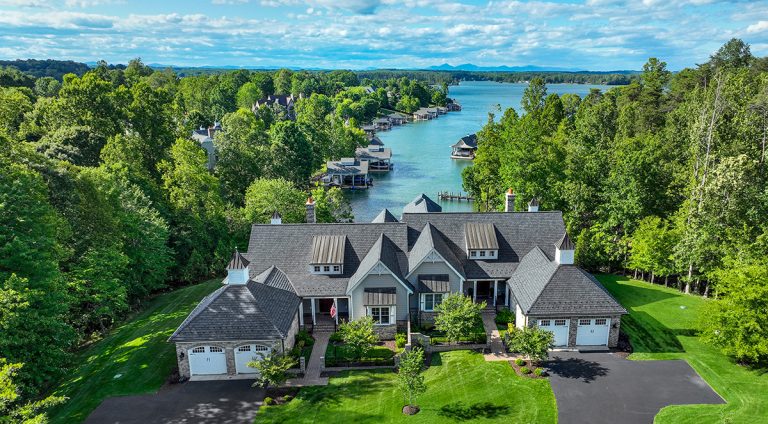 Shoreline exterior view of home framed by mature trees and water on the charity home tour.
