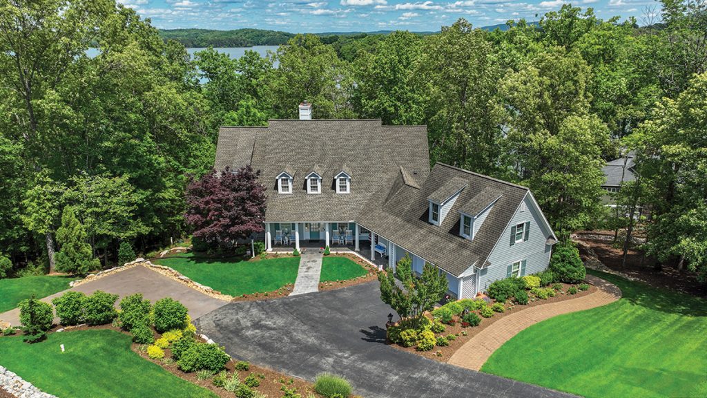 Front exterior of lake home with neutral facade and distant water views on the charity home tour.