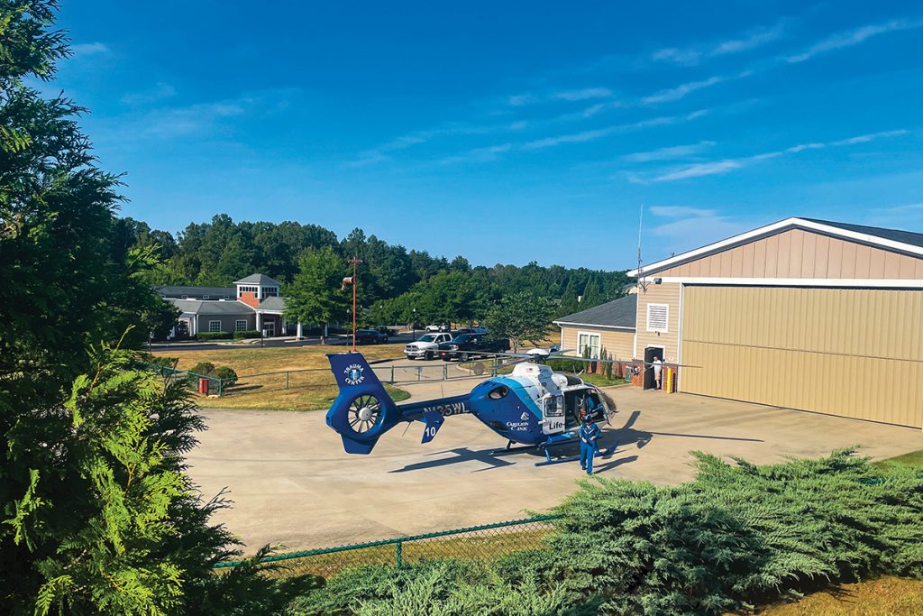 Carilion Life-Guard air ambulance helicopter on landing pad near medical facility in rural Virginia setting