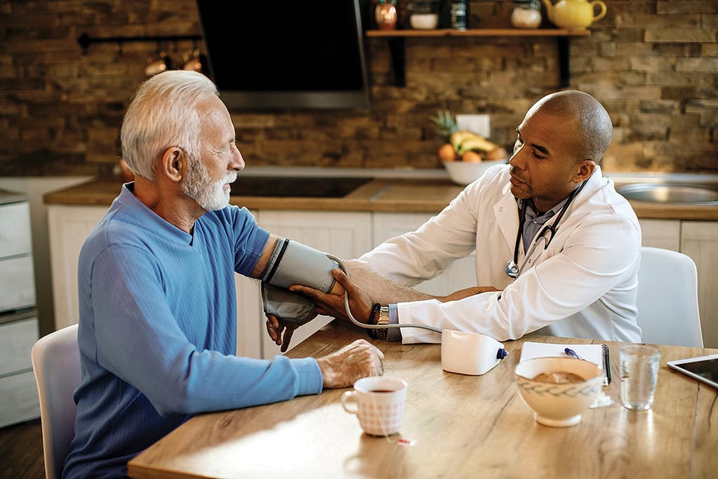 In-home healthcare provider conducting blood pressure check for senior patient in comfortable home setting