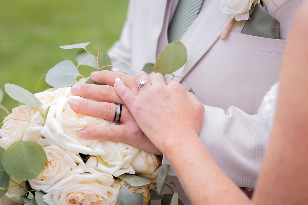 Bride and Groom holding hands with wedding rings and bouquet at Parkway Marina at Smith Mountain Lake