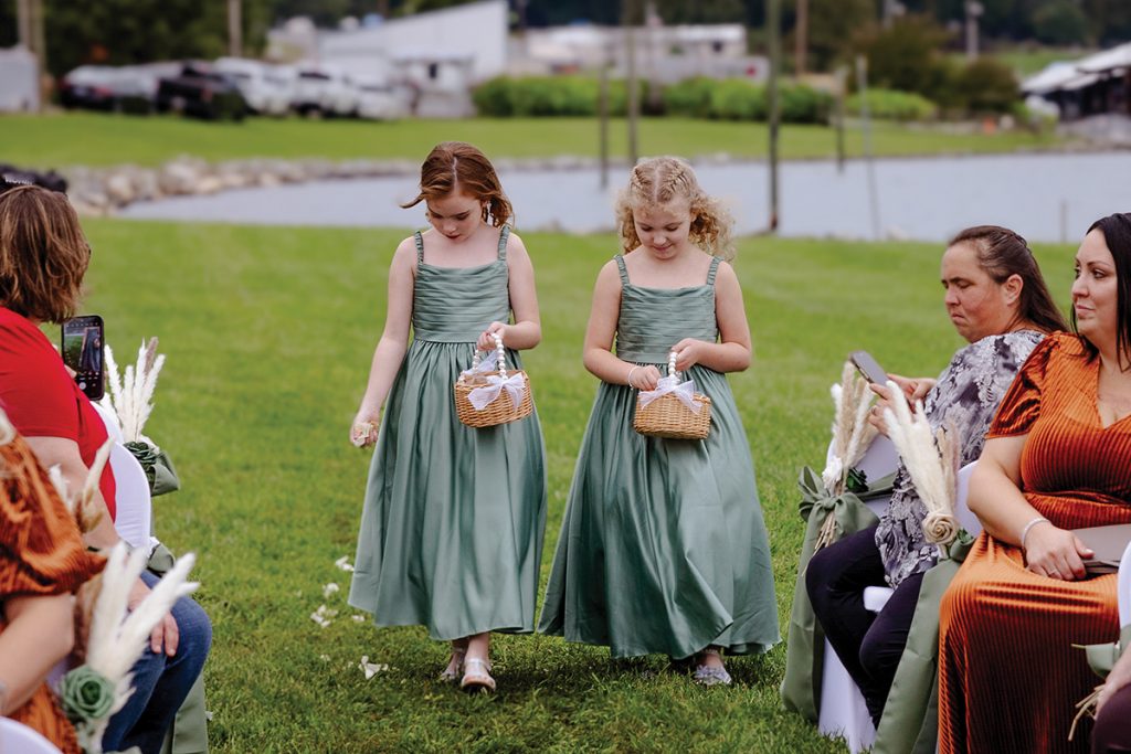 Wedding procession with flower girls tossing petals passes guests at Parkway Marina at Smith Mountain Lake