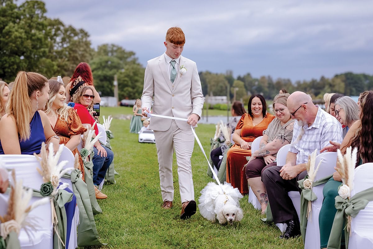 Wedding procession with ring bearer and dog passes guests at Parkway Marina at Smith Mountain Lake