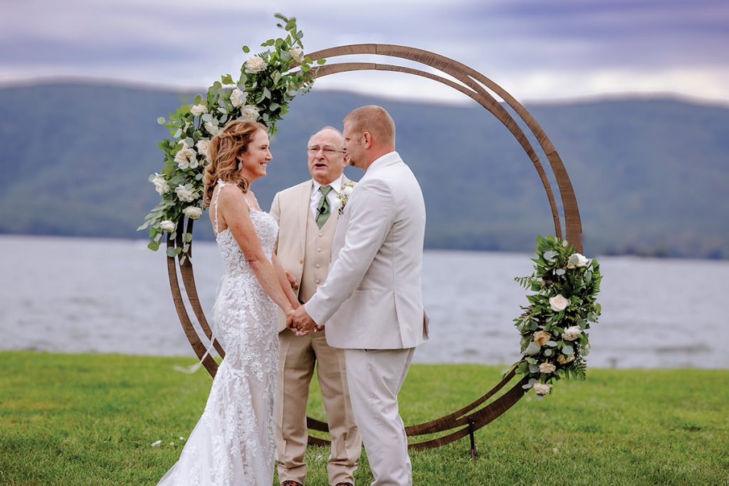 Exchanging wedding vows during lakeside ceremony at Parkway Marina with officiant and guests at Smith Mountain Lake