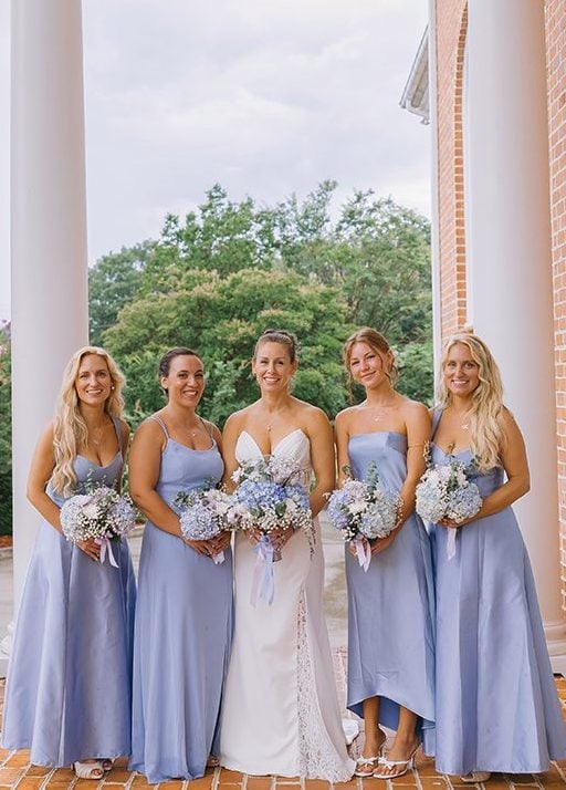 A bride and her bridesmaids stand on the brick porch at Smith Mountain Manor wedding venue, photographed by Amative Creative