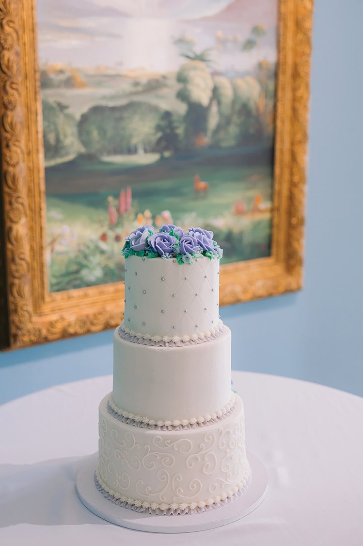 Three-tier white wedding cake with pearl details and blue hydrangea topper at Smith Mountain Manor, photographed by Amative Creative