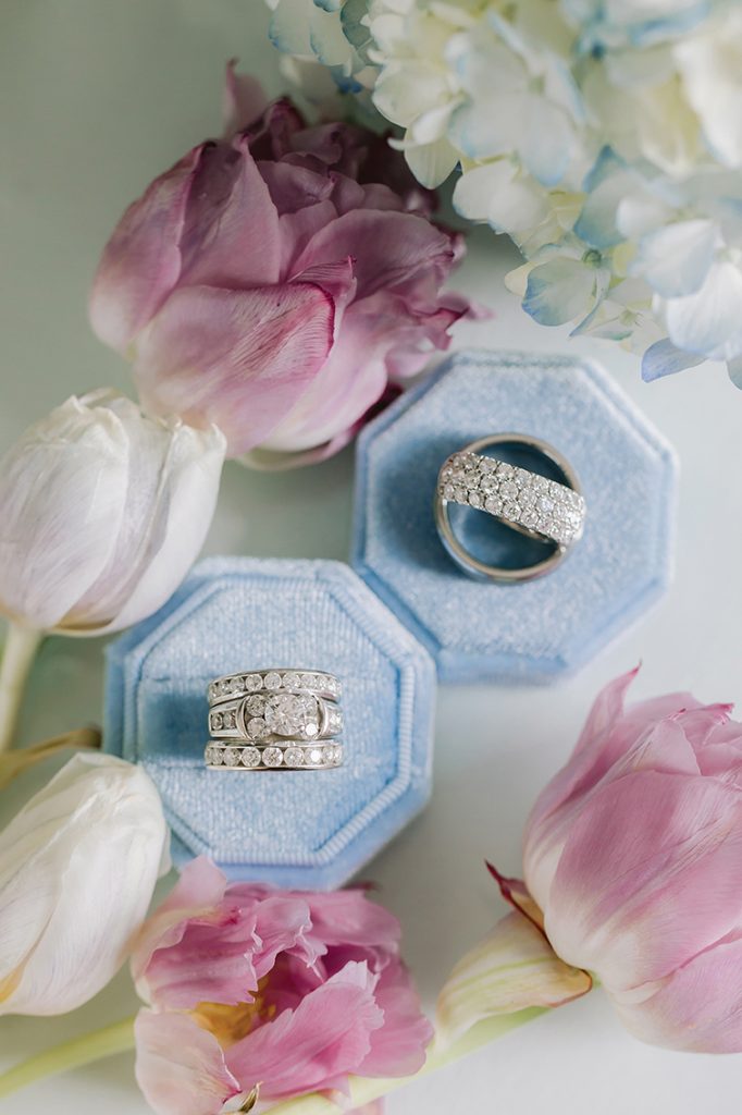 Wedding rings seated in blue velvet ring boxes with pink floral accents at Smith Mountain Manor photographed by Amative Creative