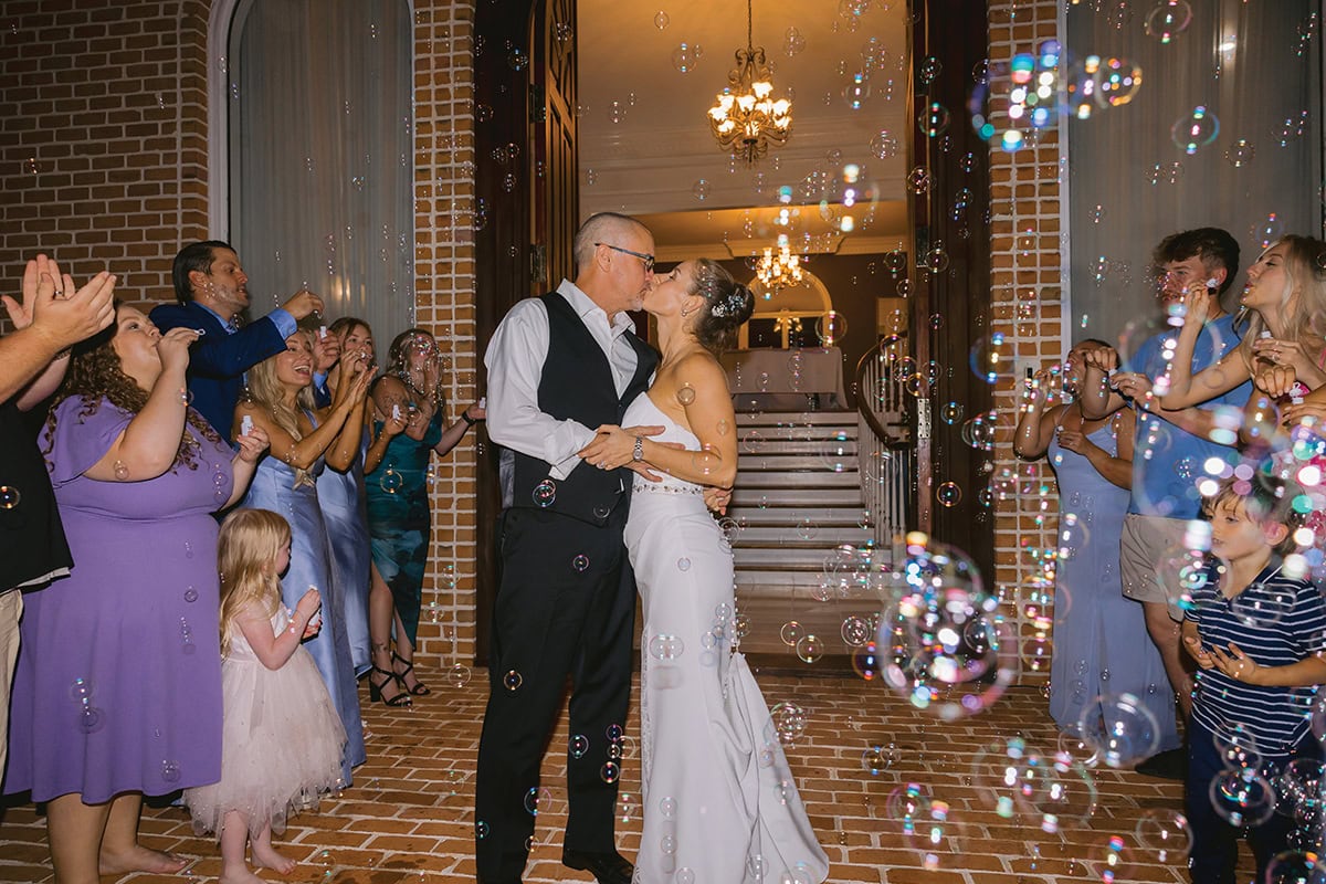 A bride and groom walk out for a bubble send off at Smith Mountain Manor wedding venue, photographed by Amative Creative