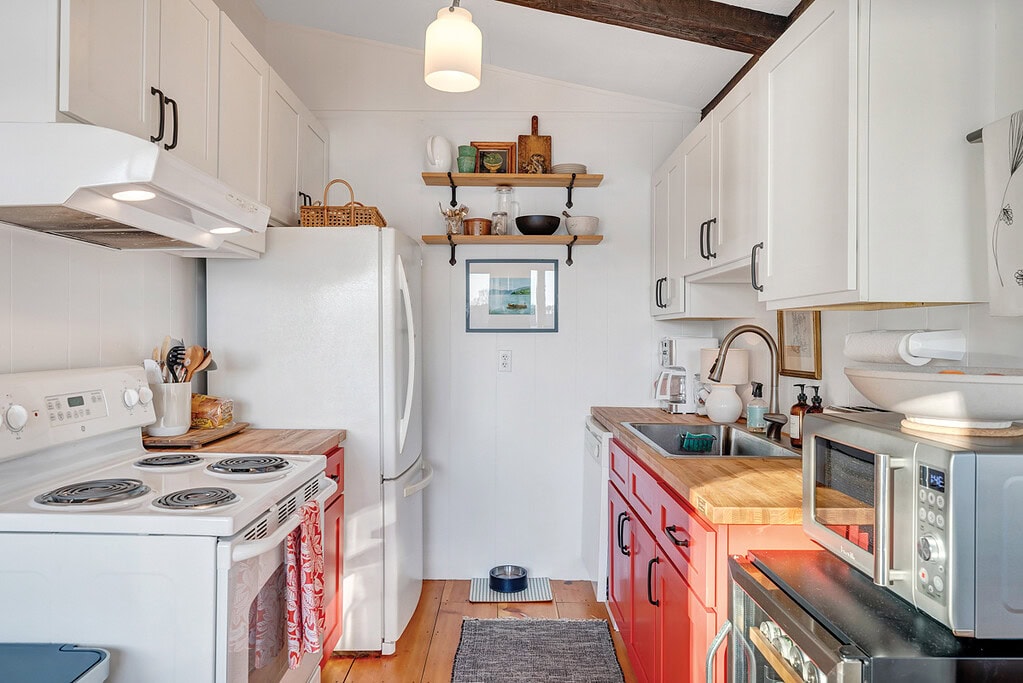 Bright, white kitchen with red lower cabinets and butcher-block counters in a Smith Mountain Lake cottage renovation.
