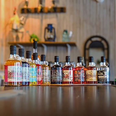 Colorful bottles of spirits lined up on the bar of a Smith Mountain Lake distillery at Bridgewater Plaza.