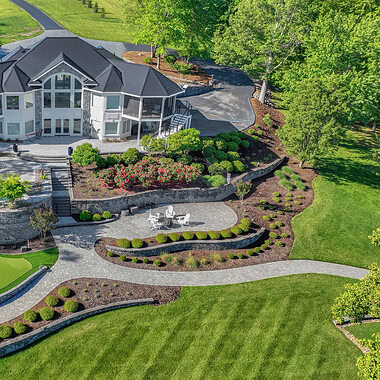 Aerial view of beautiful lakefront home with pool and putting green.