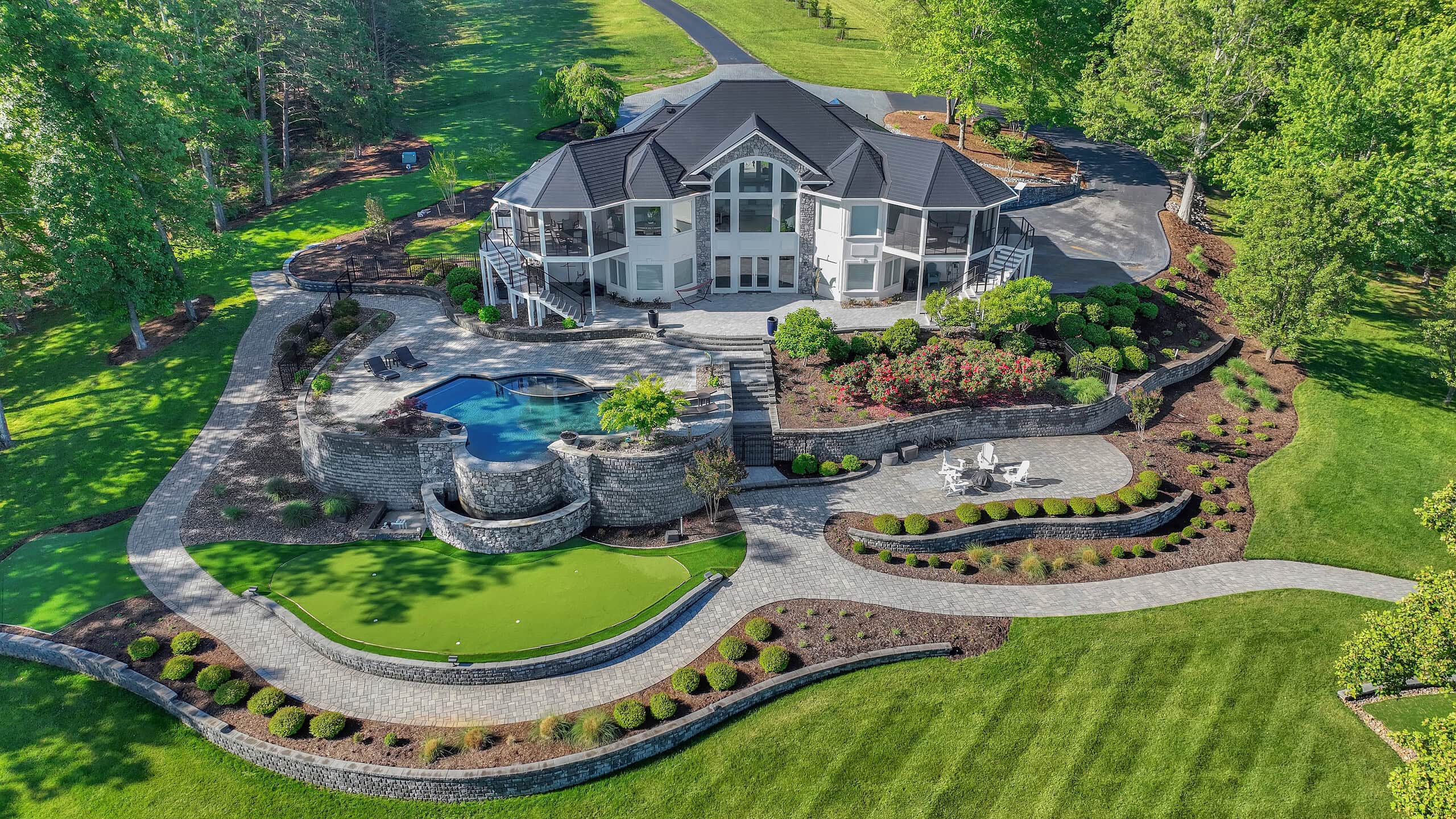 Aerial view of beautiful lakefront home with pool and putting green.