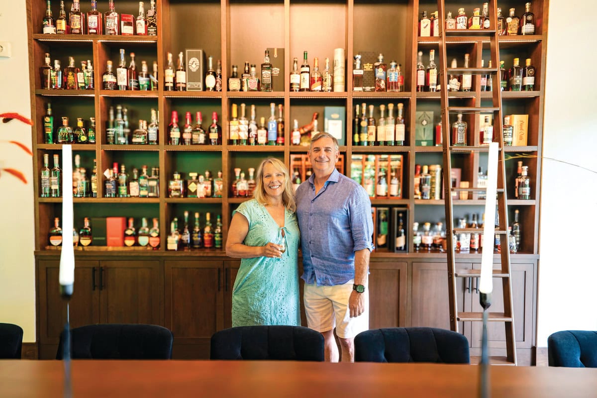 Jeannie and Rob LaBella in front of their custom shelves holding treasured bottles of bourbon