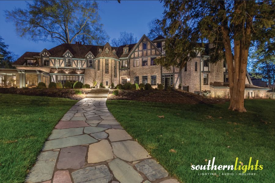 Exterior of a home at dusk with beautiful outdoor lighting installed around the walkway and landscaping
